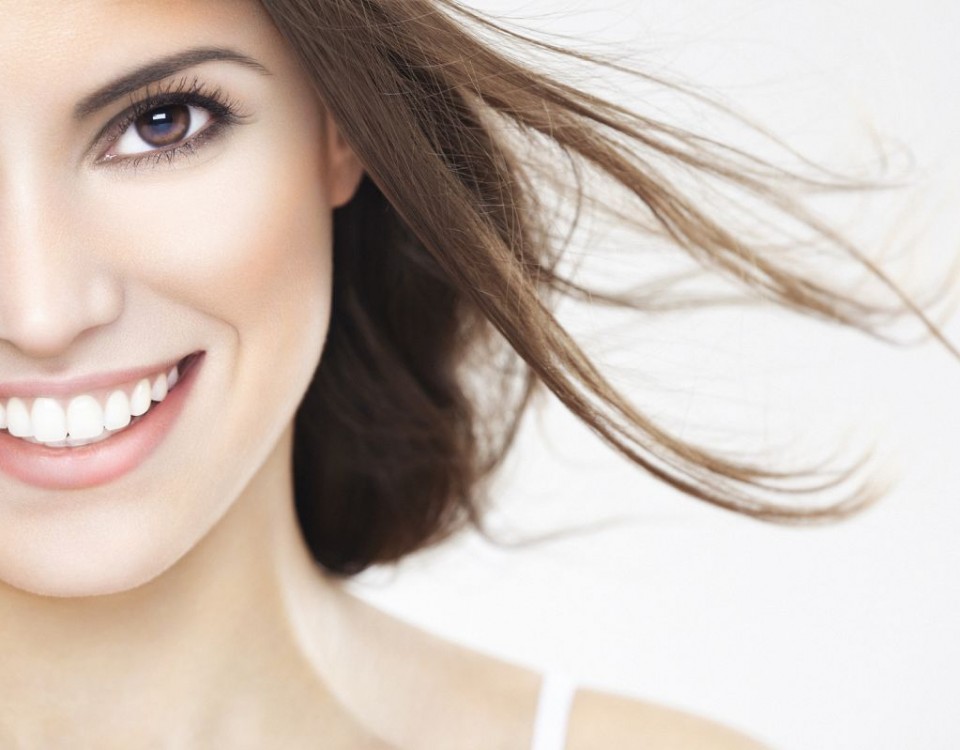 Close-up, beauty portrait of a young brunette woman with beautiful smile and fluttering hair. Shallow DOF. Developed from RAW; retouched with special care and attention; Small amount of grain added for best final impression. Adobe RGB color profile.